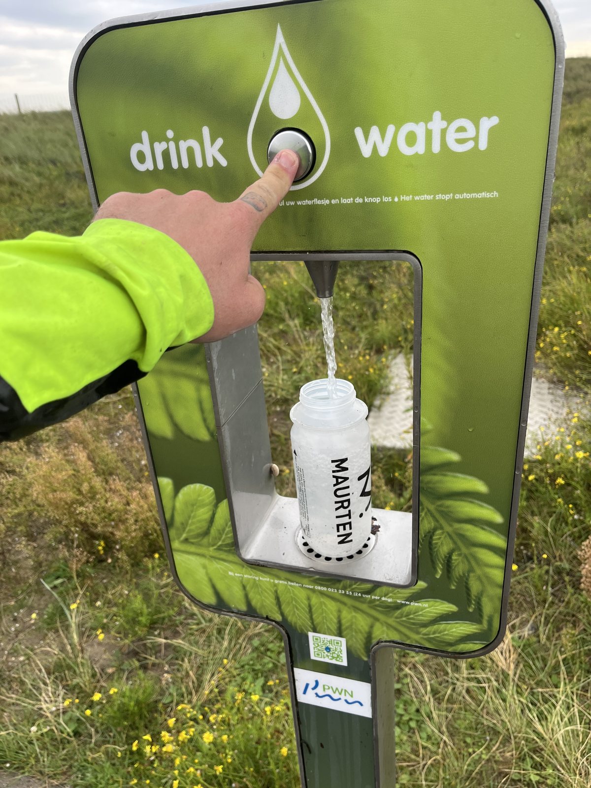 A public drinking water tap beside a cycling route, filling a bottle